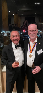 Dr. Michael Njo posing at a formal event beside a medal recipient