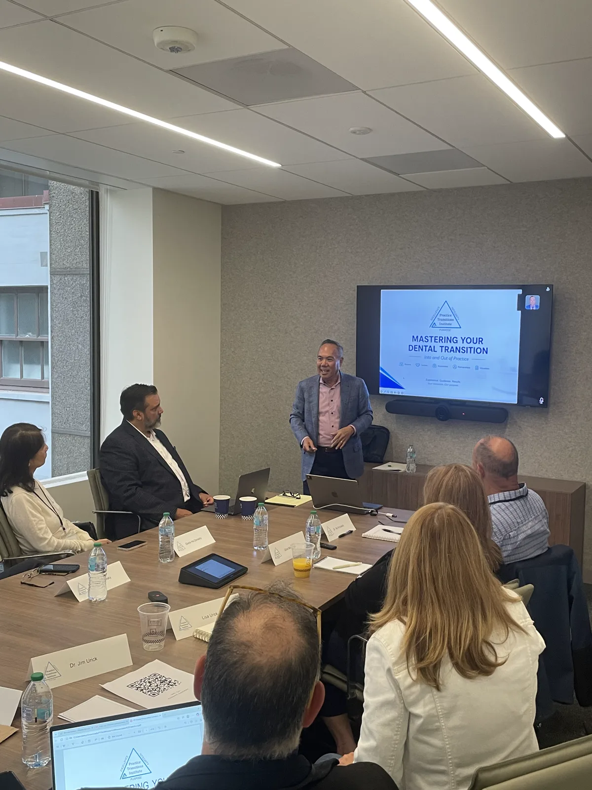 Dr. Michael Njo presenting Mastering Your Dental Transition to dentists seated around a boardroom table at the July 2026 San Francisco seminar